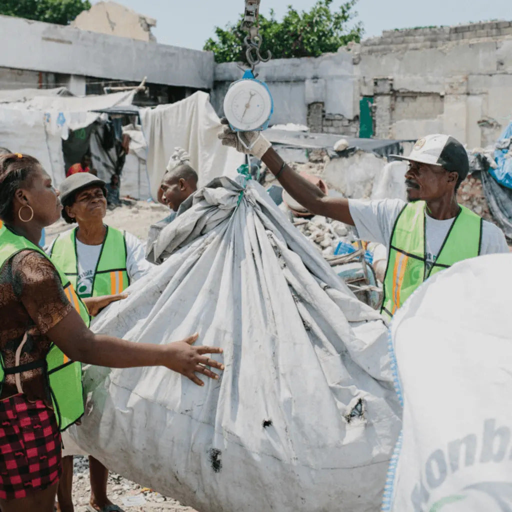 A photo of workers in Plastic Bank in Haiti. They are holding a large bag of plastic.