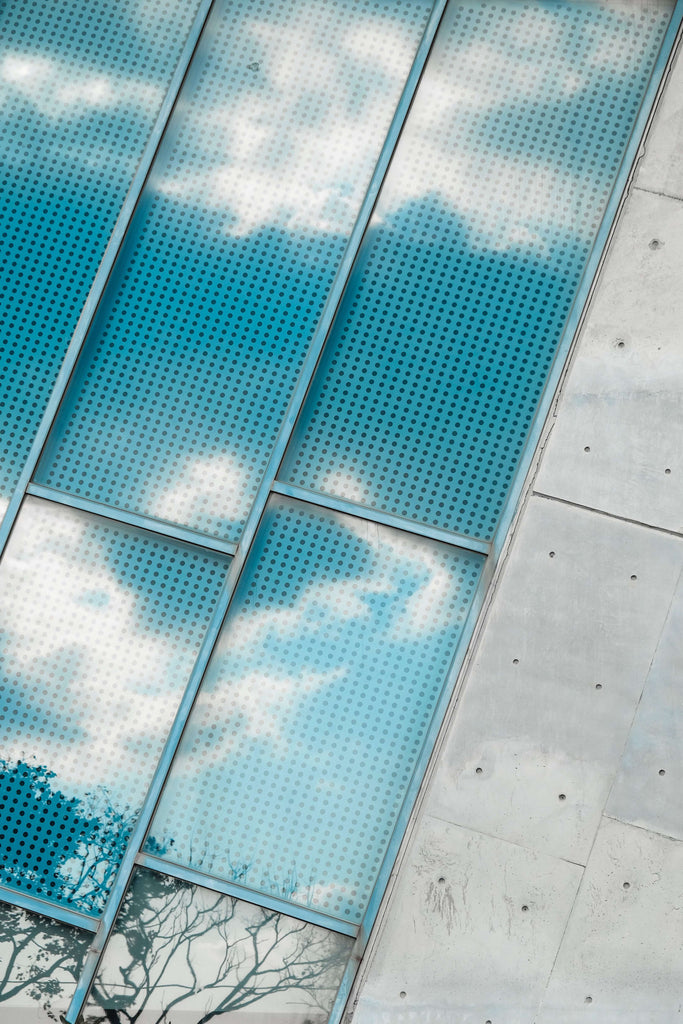 An image of solar panels reflecting a blue sky with clouds in it.